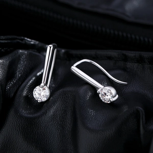 Elegante S925 Silber-Ohrhänger mit rundem Moissanit auf schwarzem Lederhintergrund