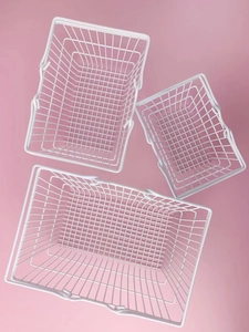Three white mesh iron storage baskets with movable handles on a soft pink background
