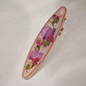 Detail of floral resin hair clip featuring pink base, real dried flowers, and gold beads