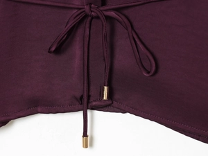 Détail du tissu satiné prune avec cordon de serrage et embouts métalliques dorés