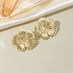 Detailed close-up of 18k gold flower petal earrings with textured radial lines