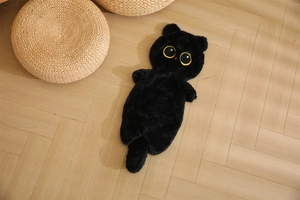 Macro detail of black plush cat pillow shell with yellow eyes on a wooden floor