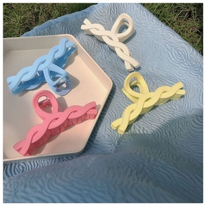 Close-up of pastel macaron colored hair claws in pink blue and yellow on fabric