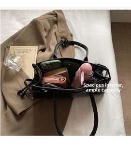 Interior view of black patent leather tote bag showing spacious capacity with personal items