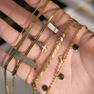 Detail of five types of 18K gold-plated stainless steel anklets with cross and leaf charms