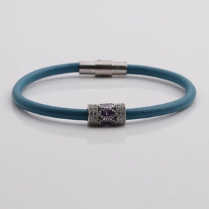 Detail of blue leather bracelet featuring a purple zircon bead and silver magnetic clasp