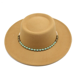 Detail of camel wool felt flat top hat featuring bohemian turquoise bead and gold trim