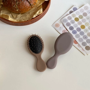 Vista dettagliata delle mini spazzole per capelli massaggianti in marrone e grigio opaco