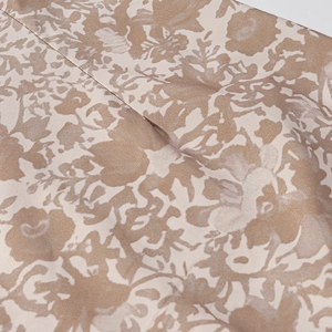 Gros plan sur la texture du tissu floral marron de cette robe licou à franges