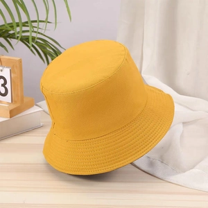 Detailed view of yellow bucket hat with reinforced stitching on a natural wood surface