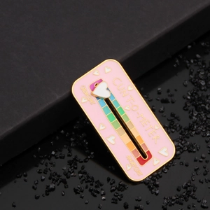 Macro view of a pink enamel Cunt-O-Meter brooch with rainbow slider and heart pointer