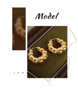 Close-up of gold U-shaped hoop earrings with unique bubble design on velvet tray