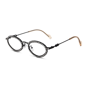 Oval rhinestone sunglasses with black metal frame and amber tips in a luxury fashion style