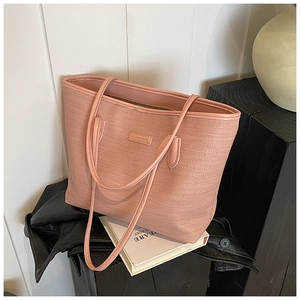 Detailed view of pink tote bag featuring woven texture and fashion metallic logo plate
