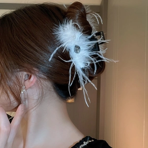 Detail of elegant hair claw clip with soft white feathers and a central crystal on hair