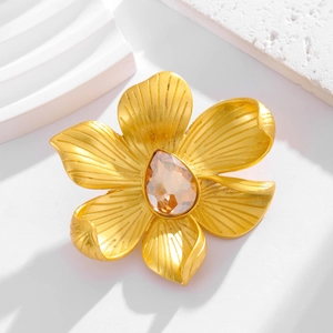 Elegant gold camellia flower brooch with an amber teardrop crystal on a studio backdrop