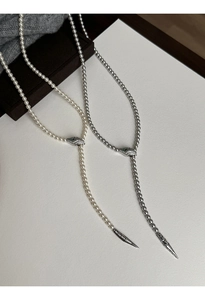 Detail of snake head pendants with emerald eyes on pearl and silver Y-necklaces