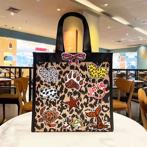 Leopard print tote bag featuring colorful embroidered patches in a cozy cafe setting