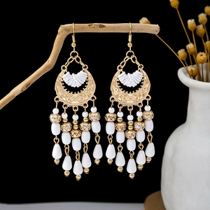 Detailed shot of bohemian gold earrings with white beads and multi-layer tassels