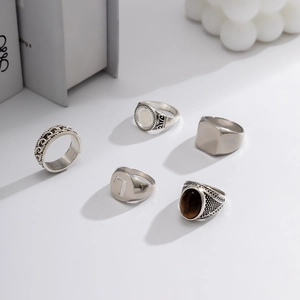 Detail of five-piece men's vintage silver ring set with brown gemstone and metal textures