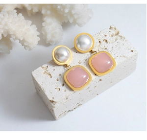 Close-up of elegant gold earrings with white imitation pearls and pink gemstone drops