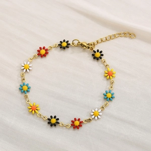 Detailed shot of golden chain bracelet featuring colorful enamel daisy charms and lobster clasp