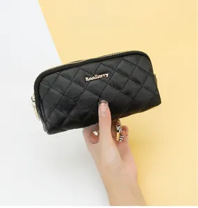 Detail of black quilted long wallet with double zipper and gold logo held by a model
