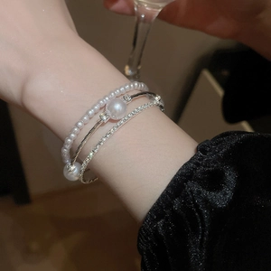 Dettaglio del set di bracciali a tre strati con perle finte, strass e lega argentata