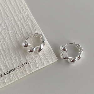 Macro detail of silver twisted rope hoop earrings with polished metal texture