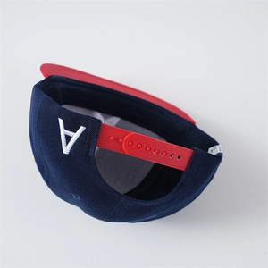 Detail of adjustable red snapback closure on navy blue baseball cap with embroidery