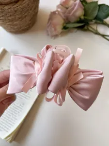 Detail of a light pink satin bow hair claw clip with a glossy finish for hair styling