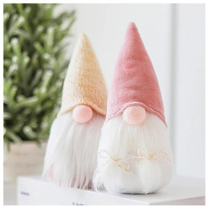 Close-up of pink velvet and yellow knit Christmas gnomes with long white faux fur beards