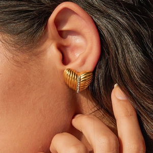 Macro shot of gold crumpled heart earrings with sparkling rhinestones on model