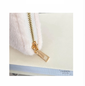 Makro-Detail des hochwertigen goldenen Metall-Reißverschlusses an der weichen Plüschbörse