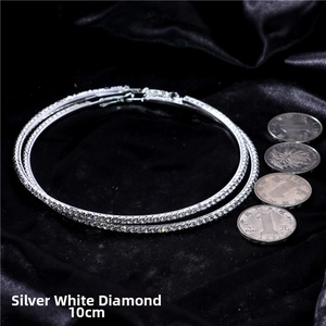 Macro shot of 10cm oversized silver hoop earrings with white zircon on black velvet