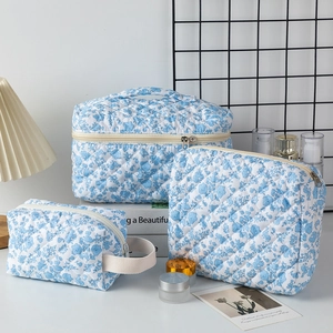 Three-piece quilted cotton makeup bag set with blue floral pattern and metal zippers