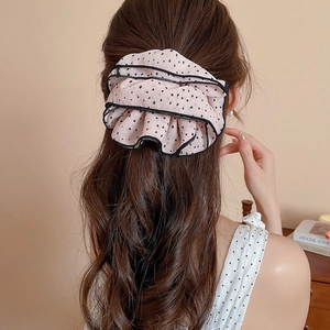 Close-up of pink polka dot ruffled scrunchie worn on long hair for a sweet retro look
