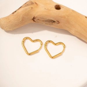 Detailed view of heart-shaped gold-plated stainless steel earrings on a natural wood branch