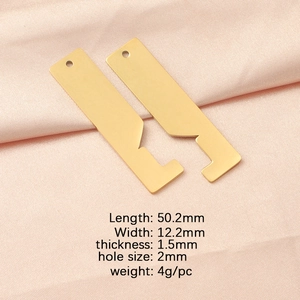 Detailed macro view of two gold stainless steel house pendants on pink fabric