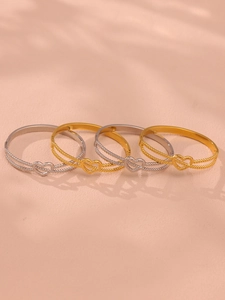 Détail des bracelets cœur à double rangée perlée en or et argent sur fond pêche doux