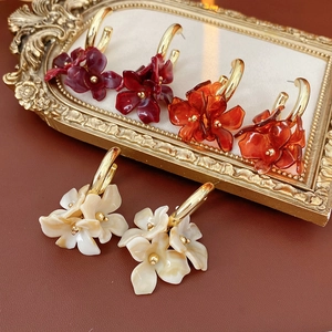 Detailed shot of resin flower petal earrings in burgundy, amber, and cream with gold hooks