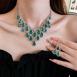 Detail of silver drop-shaped green gemstone necklace and tassel earrings on model