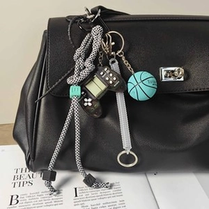 Dettaglio di un ciondolo borsa street style con corda intrecciata e mini basket decorativo
