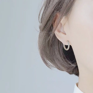 Macro detail of silver twisted rope textured hoop earrings on female model