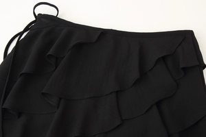 Detail of black tiered ruffle skirt with delicate waist ties and lightweight texture