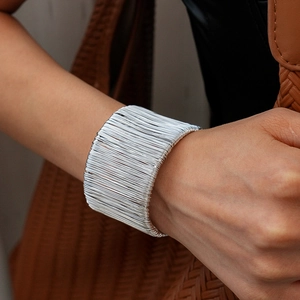 Detail of silver layered wire wrap cuff bracelet with thick metallic texture on wrist