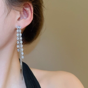 Detail of silver long tassel earrings with marquise-cut crystals on a female model