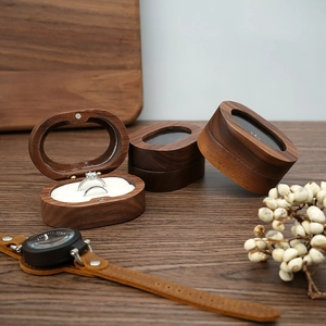 Detail of walnut wood ring box with white foam lining on a wooden desk with dried flowers