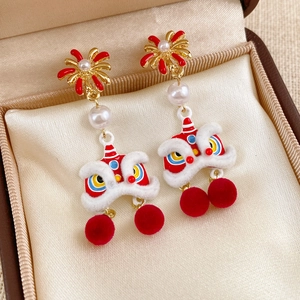 Detail of lion dance earrings with red pom-poms and pearl accents on satin