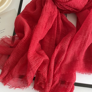 Detail showing red linen scarf texture with pleated fabric and raw fringe edges